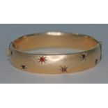 A yellow metal bangle set with red paste.