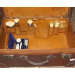 A vintage brown leather fitted travel case with ivory and hallmarked silver bottles, brushes and