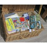 A wicker basket with stamp albums, loose stamps, postcards and cigarette cards