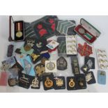 A box of British cap badges, cloth badges and medals.