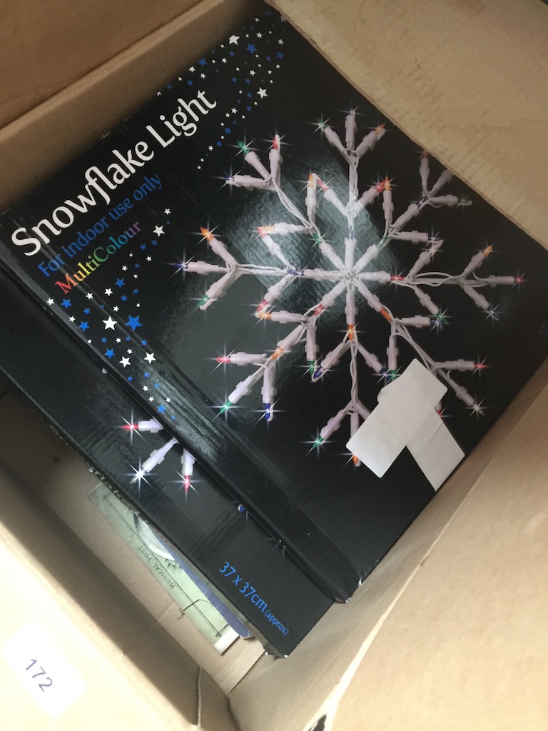 A box with snowflake lights, books, old newspapers, etc Catalogue only, live bidding available via