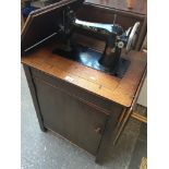 A Singer treadle sewing machine in cabinet Catalogue only, live bidding available via our website.