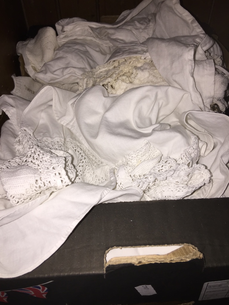 A box of mainly Victorian / Edwardian clothing to include tops, christening gowns, WW2 era clothing,