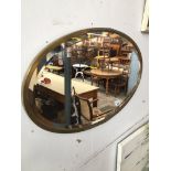 An oval brass framed bevelled edge mirror Catalogue only, live bidding available via our website.