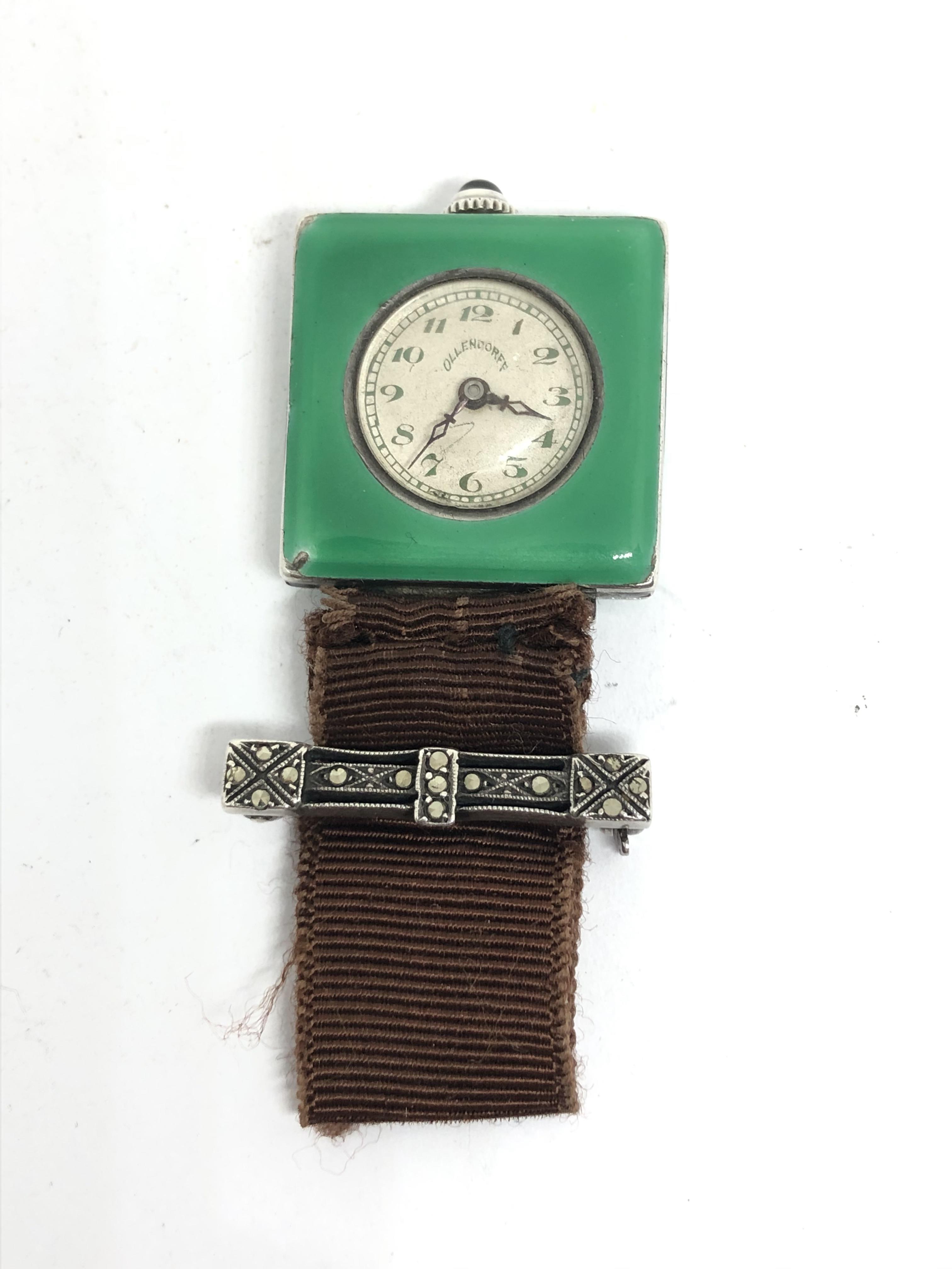 An Ollendorff silver and green enamel case lapel watch with signed 15 jewel manual wind movement