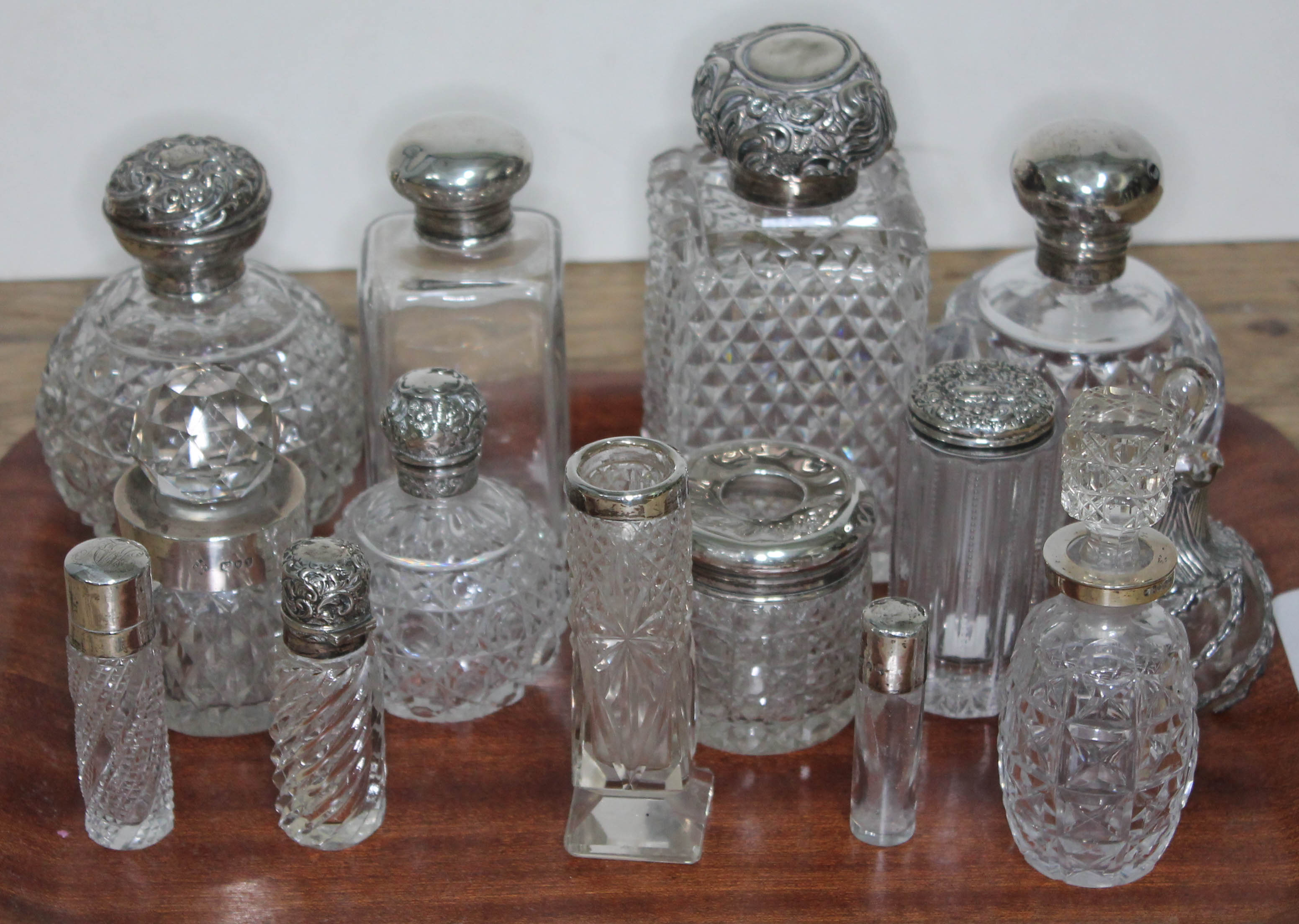 A group of fourteen hallmarked silver topped or mounted glass bottles and jars, tallest 14cm.