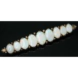 A precious opal brooch featuring nine opal cabochons, length 68mm, rafted in yellow metal, unmarked,