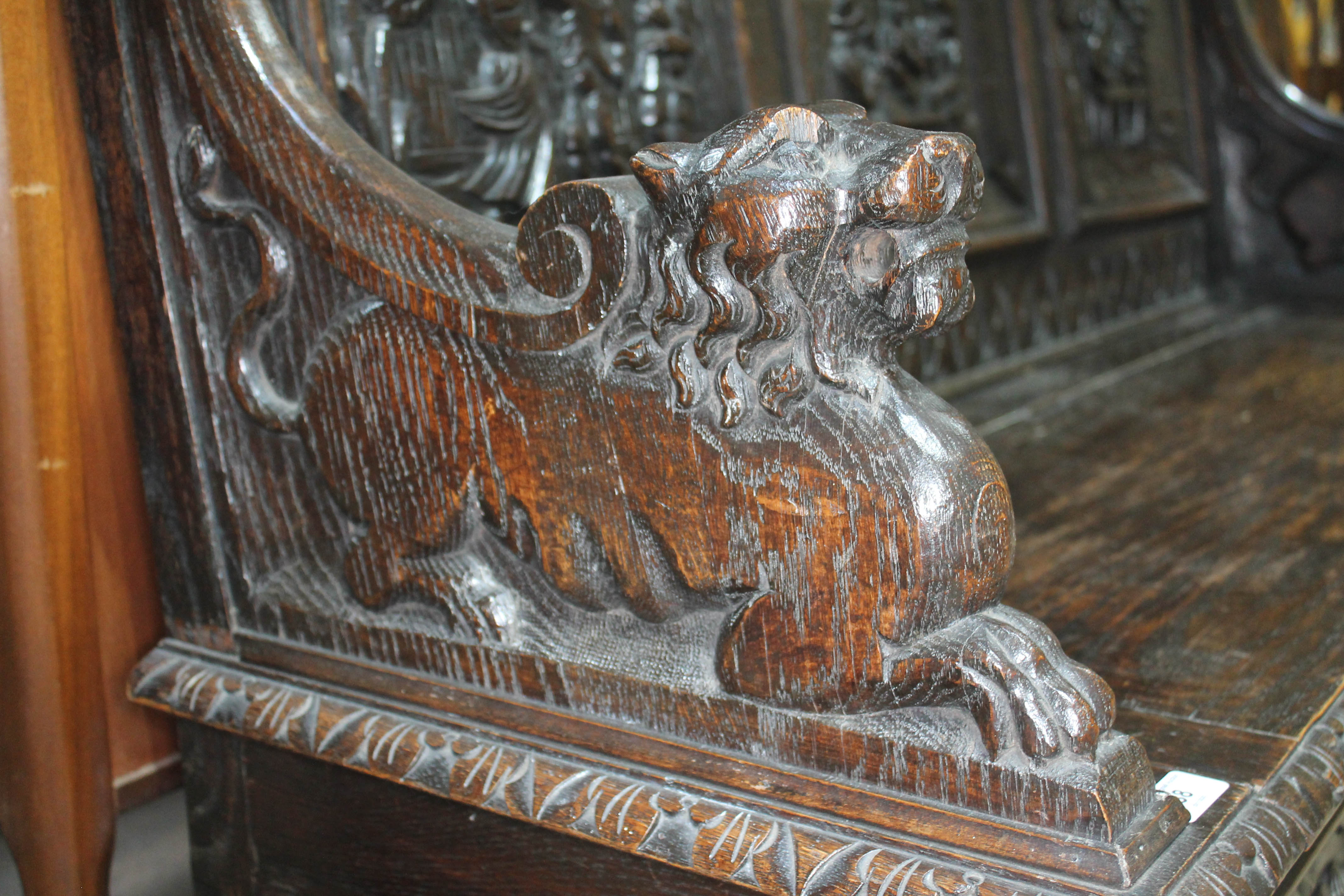 A 19th century carved oak settle with lion arms, carved continental scene panels to back, lift top - Image 3 of 4