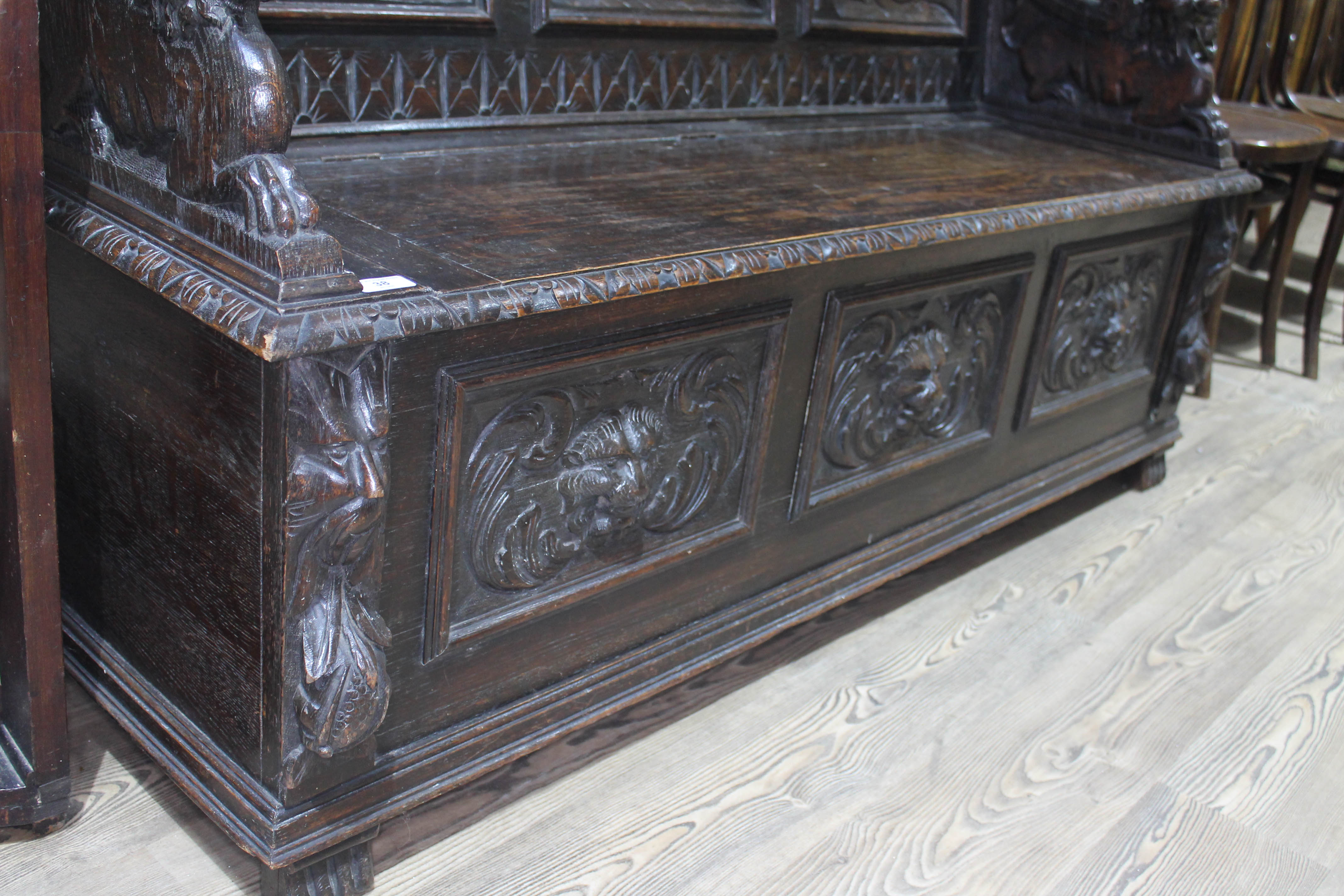 A 19th century carved oak settle with lion arms, carved continental scene panels to back, lift top - Bild 2 aus 4