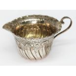 A bright cut engraved and embossed hallmarked silver cream jug and a mustard spoon, wt. 3oz.