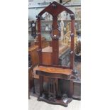 A Victorian mahogany arched top gothic hall stand with turned hooks, singular round mirror, lidded