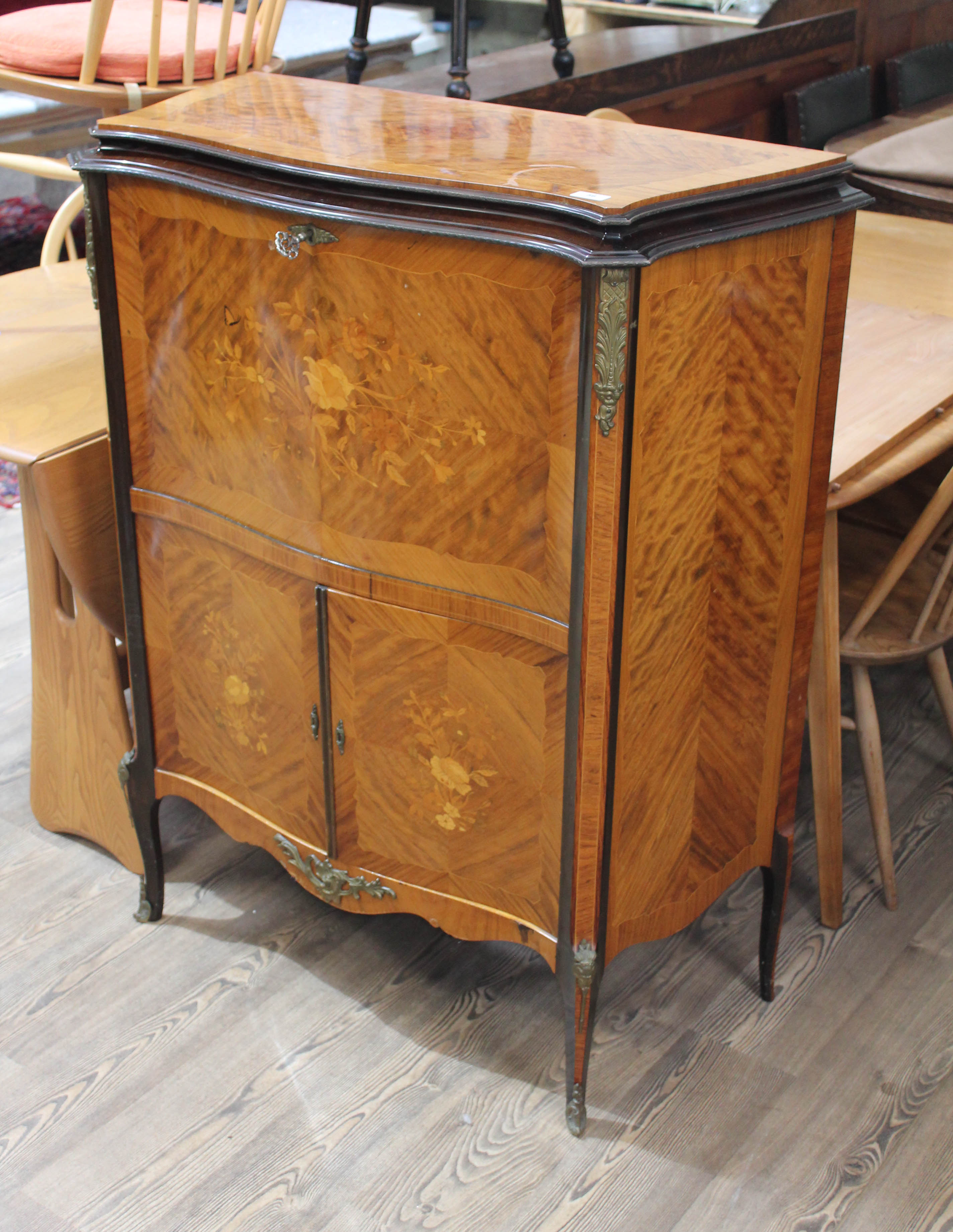 A French serpentine kingwood marquetry inlaid drinks cabinet with gilt metal mounts and floral