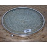 A hallmarked silver mounted glass teapot stand with central lace panel, stood on three feet,