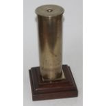 A gong formed from a German brass shell case on oak plinth, height 29cm.