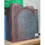 A studio pottery ornament in the shape of a Lego brick with a spiral design to the front