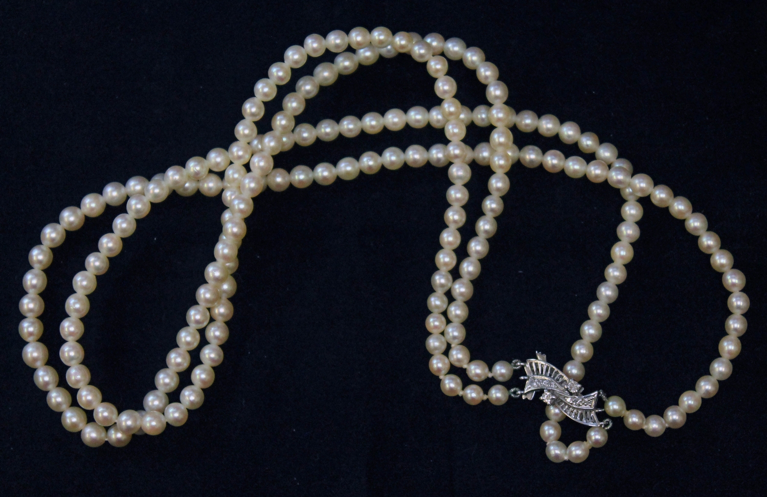 A two strand cultured pearl necklace with white metal diamond set clasp marked '9c', pearls