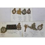 A group of nine cap badges and a shoulder badge.