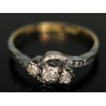 An early 20th century three stone diamond ring in cross over setting, band marked '18ct PLAT', gross