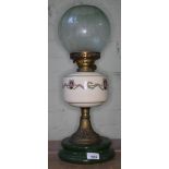 An oil lamp on green ceramic base, supported on brass column, with cream reservoir bearing floral
