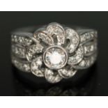 An Art Deco style flower cluster ring, millegrain setting with central modern round brilliant cut