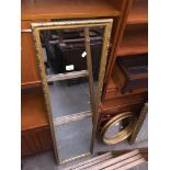 A tall gold framed mirror and a black glass tv stand Catalogue only, live bidding available via