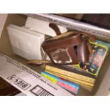 A box of misc items to include Kodak Tourist camera, hearing aid, few games and toy cars.