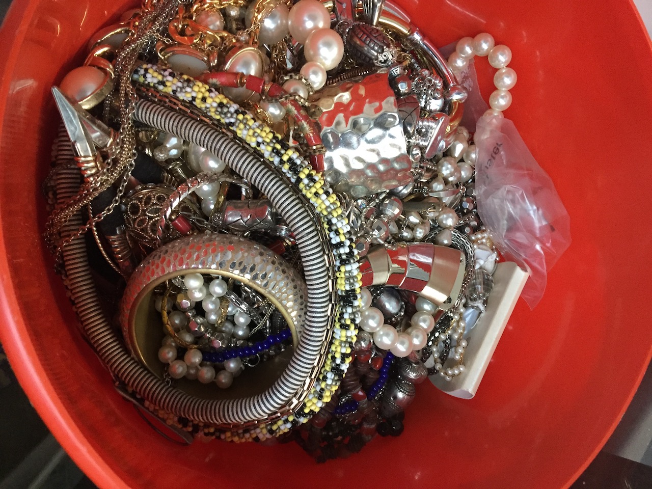 A red tub of costume jewellery. The-saleroom.com showing catalogue only, live bidding available