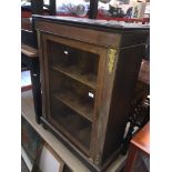 A 19th century rosewood veneered glazed single door cabinet with felt line shelves - one rear foot