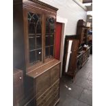 An Edwardian mahogany glazed bookcase cabinet with desk slide in cupboard over four drawers.