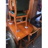 A reproduction yew wood drop leaf dining table and four chairs with studded and buttoned green