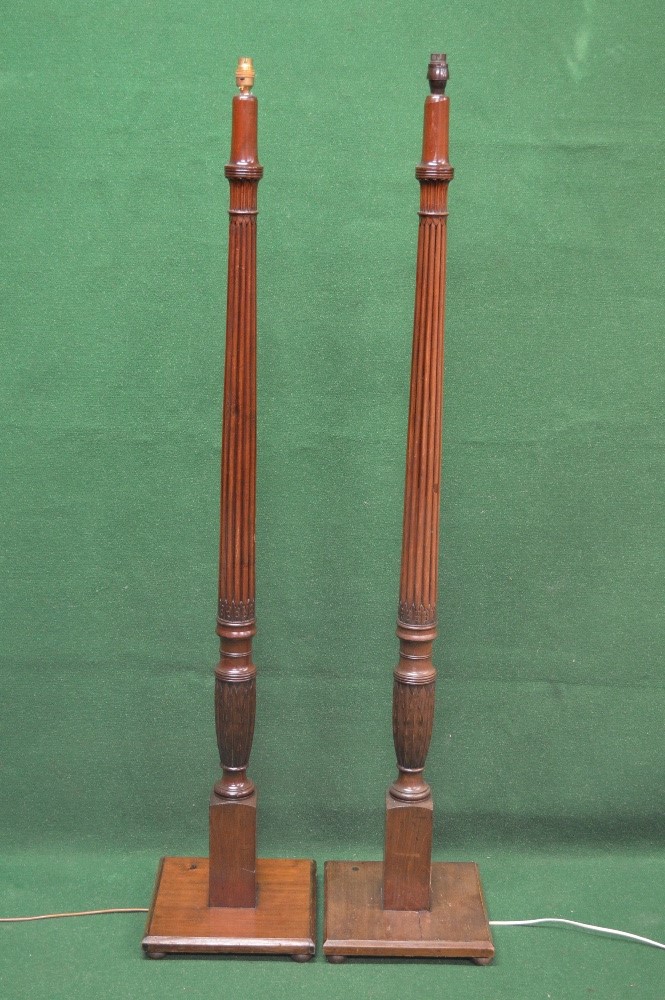 Pair of mahogany standard lamps having reeded columns leading to square bases with chamfered edges,