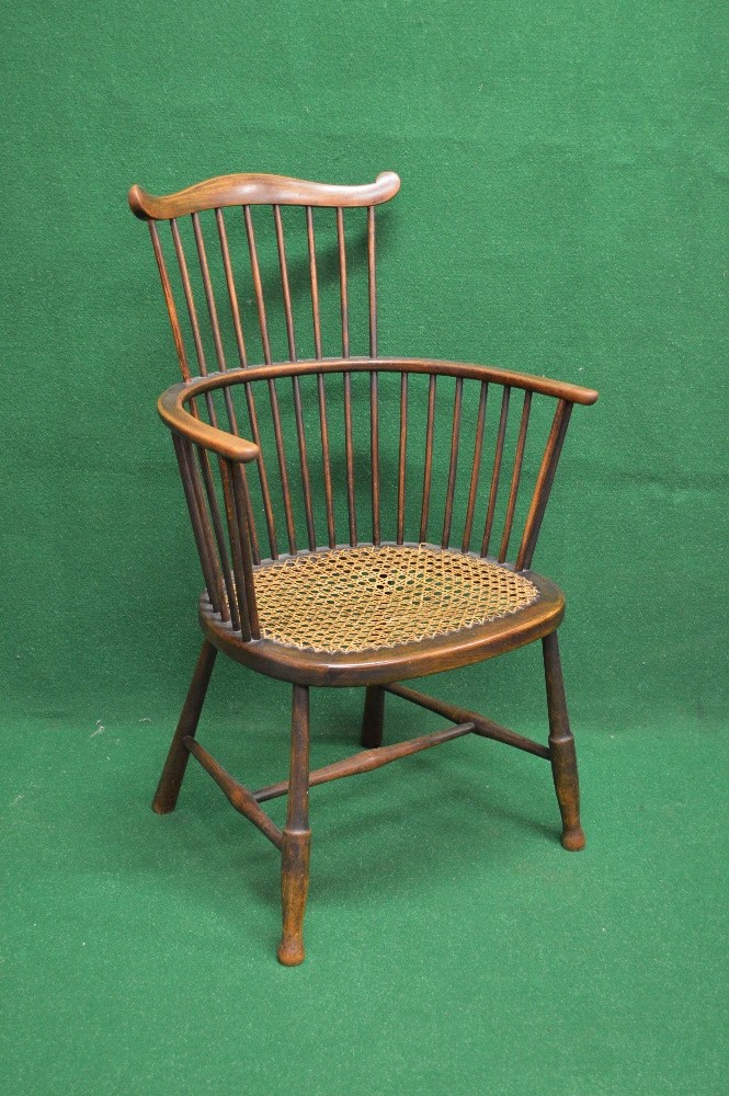 Beech framed comb back Windsor chair having cane seat and supported on turned stretchered legs