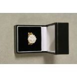 Diamond three tier yellow metal cluster ring, the central round brilliant cut diamond weighing