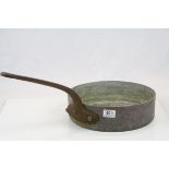An antique copper pan with iron handle