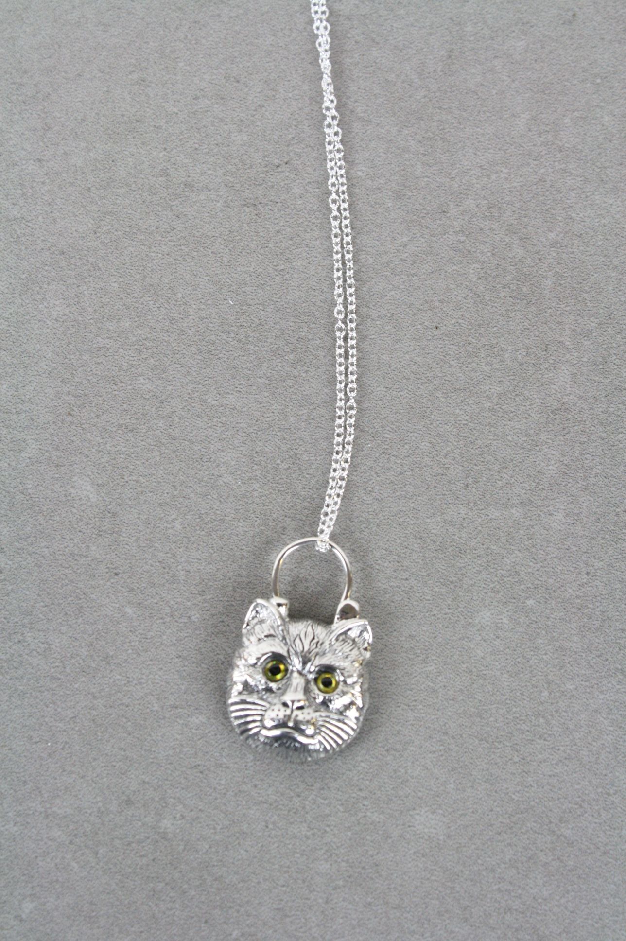 Silver pendant necklace in the form of a cat with glass eyes