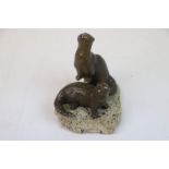 Bronze sculpture of two otters on a stone base