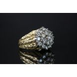 Diamond three tier yellow metal cluster ring, the central round brilliant cut diamond weighing