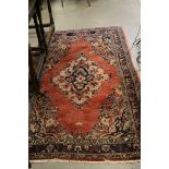 Perisan Wool Red Ground Rug decorated with a central pattern surrounded by a border, 212cms x
