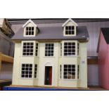 Wooden yellow and grey dolls house with front and roof opening, containing furniture and accessories