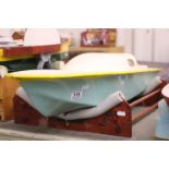 Fibreglass battery powered speed boat on wooden stand, 38" approx in length