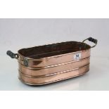 Copper Twin Handled Planter, hand made with ribbed body and raised on four ball feet, 43cms long