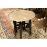 Anglo-Indian Profusely Carved Folding Table with Brass Circular Top together with another Folding