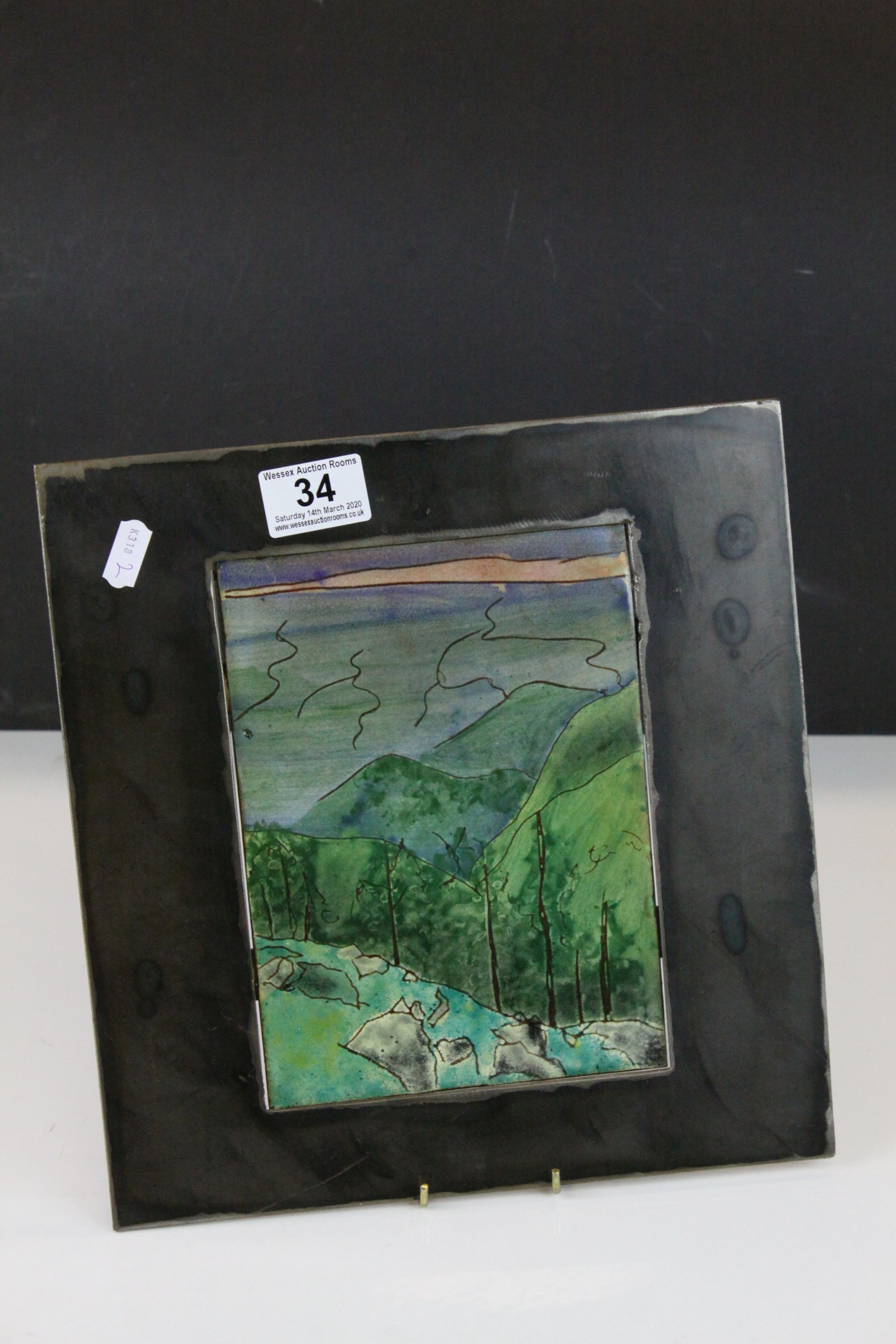 Contemporary steel framed copper plaque with enamelled decoration, rural scene with hills to