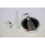 Silver and onyx cat pendant necklace sat upon a ruby platform