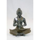 South East Asian Seated Bronze Buddha figure in costume playing a horn, 20cms in height.