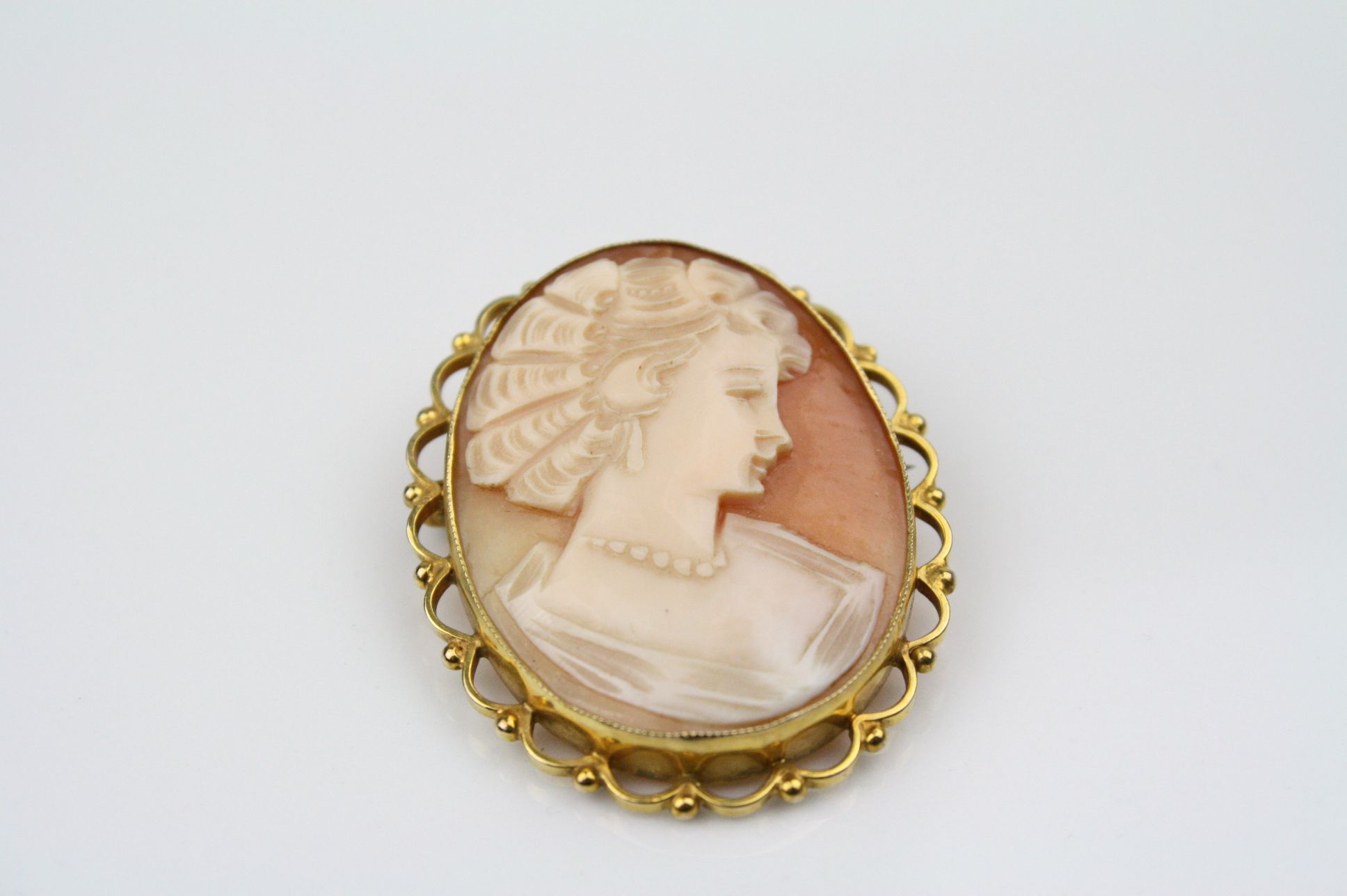 Shell cameo 9ct yellow gold brooch, the cameo depicting female profile, collet setting, scroll and