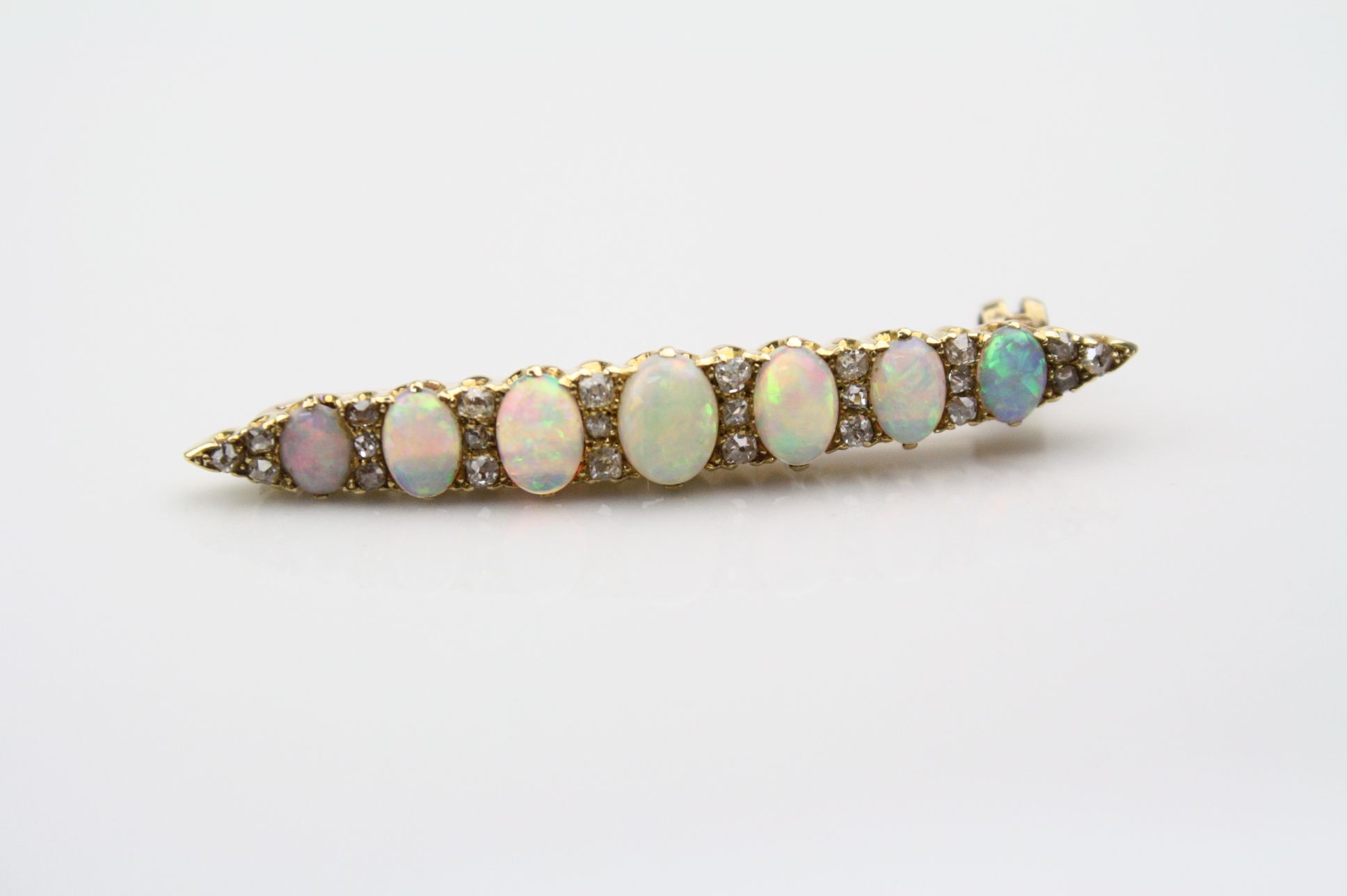 Opal and diamond yellow metal bar brooch, seven graduated precious white cabochon cut opals,