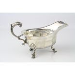 Silver sauce boat raised on three hoof feet, scroll handle with cast acanthus leaf decoration,