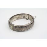 Silver hinged bangle, engraved floral and foliate scroll decoration, tongue and box clasp complete