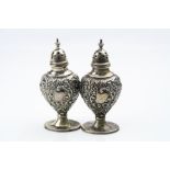 Pair of Edwardian silver pedestal pepperettes, repoussé floral and foliate scroll decoration to